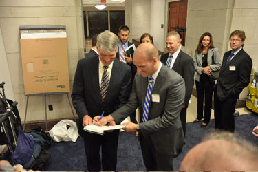 Josh Seefried, an officer in the Air Force and co-founder of OutServe, signs a copy of his book, Our Time, for Sen. Mark Udall (D-Colo.).