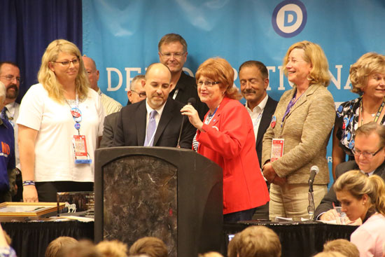 DNC director of constituency outreach, Brian Bond, left at lectern, stands with transgender DNC committee member Babs Siperstein. Dr. Dana Beyer is immediately right of Siperstein