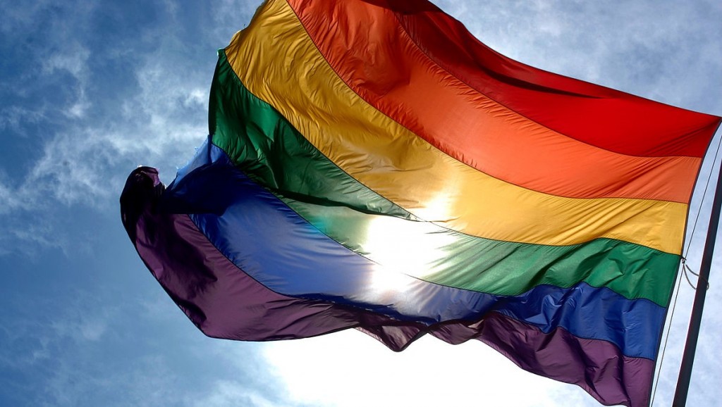 1200px-Rainbow_flag_and_blue_skies