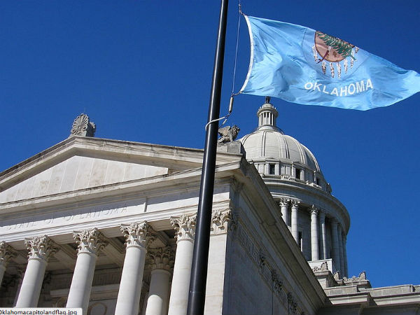 The Oklahoma Flag waving outside of the Oklahoma State Capitol (Photo: Okiefromokla, via Wikimedia).